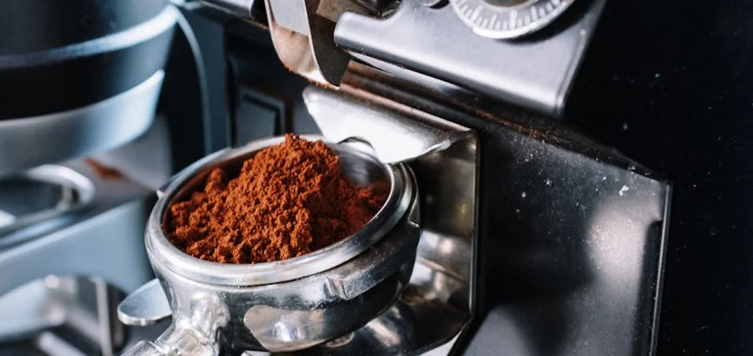 Close-up of an espresso machine portafilter filled with ground coffee.