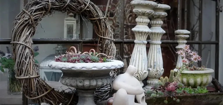 Rustic arrangement featuring a twig wreath and pedestal planters filled with succulents on a weathered windowsill.