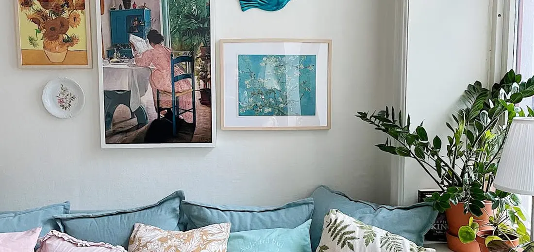 Cozy living room with potted plants by a window and wall art, illustrating indoor plant placement for proper watering and humidity