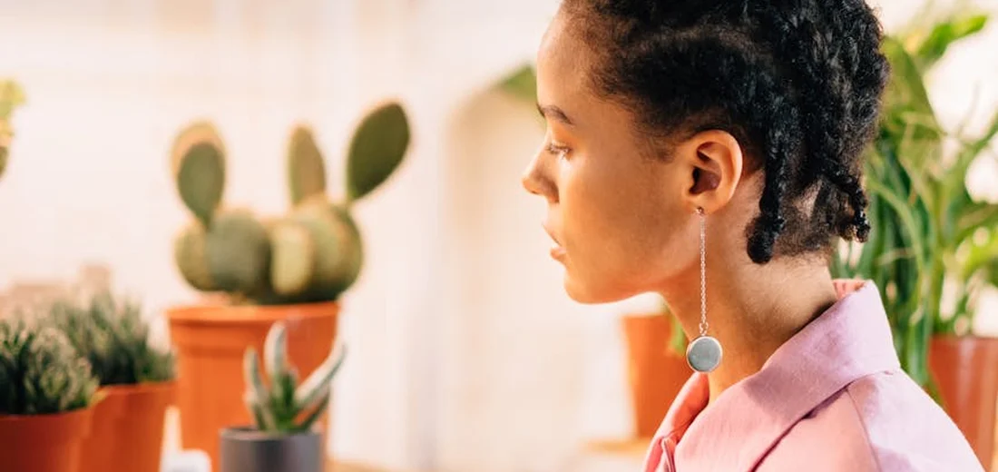 Profile of a woman indoors with potted plants and cacti in the background