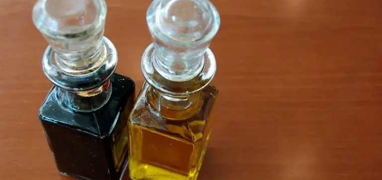 Two glass dropper bottles with dark and golden liquids on a wooden surface, representing neem oil and a spray solution for succulent pest control
