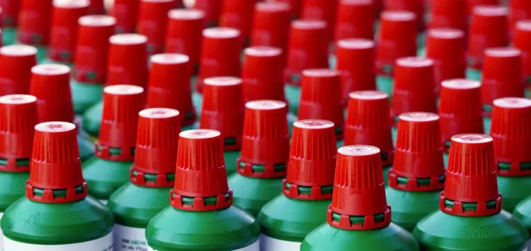 Rows of green fertilizer bottles with red caps.