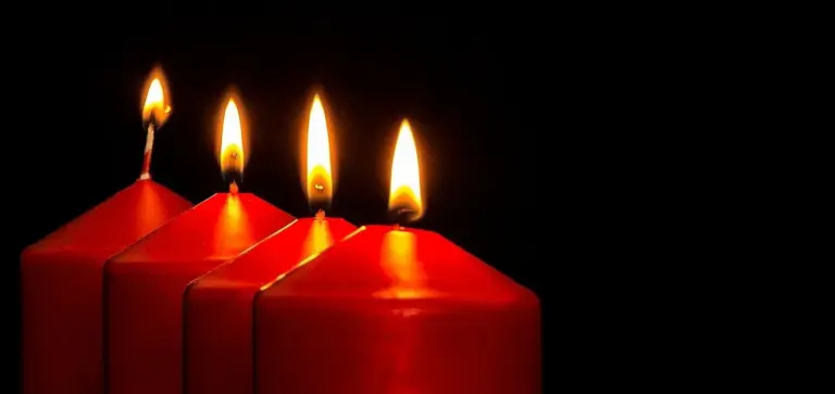 Three red pillar candles lit against a dark background