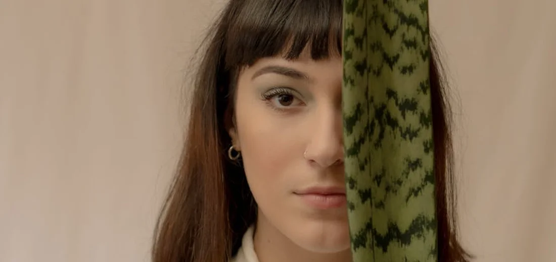 A person with a snake plant leaf partially covering their face.