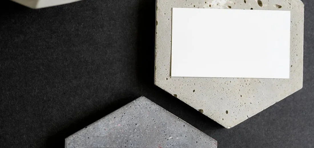 Close-up of two geometric concrete blocks on a dark surface, with a blank white label on one block.